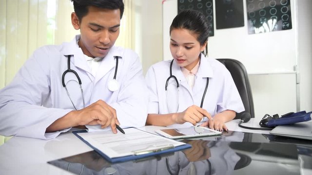 Asian female doctor discussing results of Computerized Tomography scan with asian male doctor