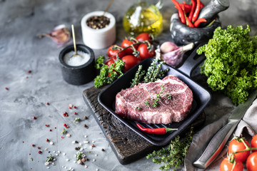 Fototapeta na wymiar Raw fresh meat. Steak for two with ingredients in a grill pan, with spices, vegetables and herbs