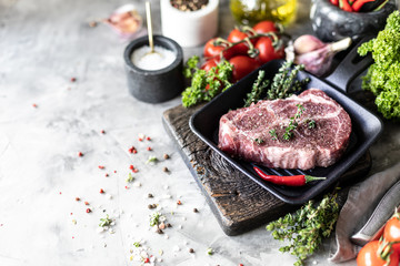 Raw fresh meat. Steak for two with ingredients in a grill pan, with spices, vegetables and herbs