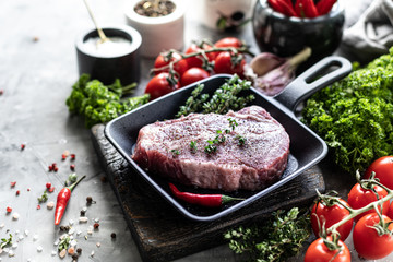 Raw fresh meat. Steak for two with ingredients in a grill pan, with spices, vegetables and herbs
