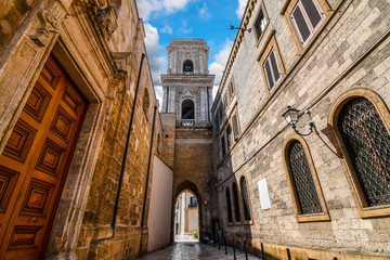 A medieval bell tower with a tunnel opens up to the ancient Piazza del duomo in the historic center of Brindisi Italy. - obrazy, fototapety, plakaty
