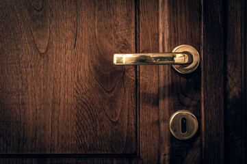 Obraz premium An old wooden door with golden handle sorrounded by black vignette