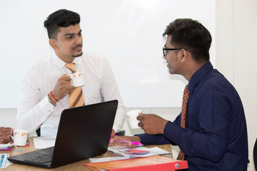 Two businessmen drinking coffee and discussing new project in conference room