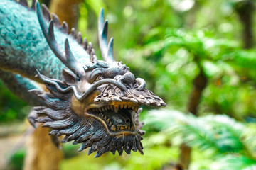 Vintage classic statue of Asian China Dragon sattle in the green garden.