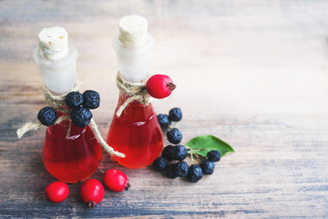 Hawthorn tincture (thornapple, May-tree, whitethorn, hawberry) in glass small bottles, black mountain ash and fresh hawthorn berries on the wooden table. Herbal medicine.