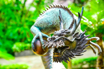 Vintage classic statue of Asian China Dragon sattle in the green garden.