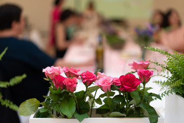 flowers decorate on the dinning long table in the luxury relax event with the blur social people behind
