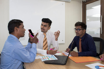 Businessman sharing mobile phone content with colleagues at office meeting