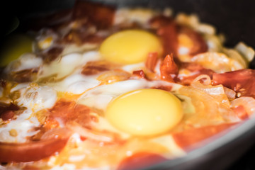 Fried eggs with onions, tomato and pepper, cooking in a pan, breakfast, healthy lifestyle