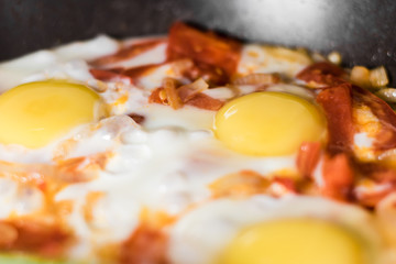 Fried eggs with onions, tomato and pepper, cooking in a pan, breakfast, healthy lifestyle