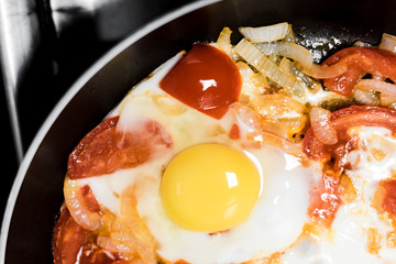 Fried eggs with onions, tomato and pepper, cooking in a pan, breakfast, healthy lifestyle