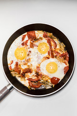 Fried eggs with onions, tomato and pepper, cooking in a pan, breakfast, healthy lifestyle