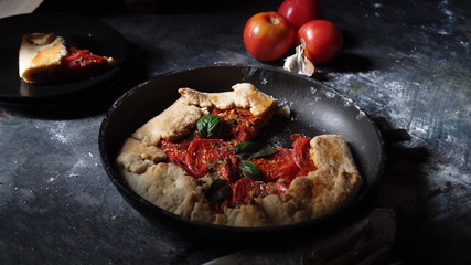 Corn galette with tomatoes and basil on the black table. Dark photo. Phohto recipe