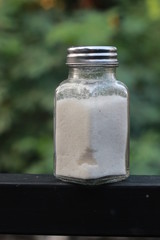salt from small shaker at garden, green background