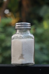 salt from small shaker at garden, green background
