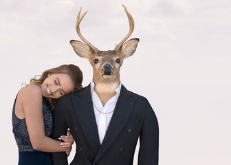 Smiling teenage girl with big buck deer in tuxedo suit isolated on soft blush pink background