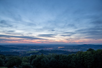 Obraz premium The setting sunset over the town of Valasske Mezirici as the city and its surroundings public light up slowly multi colored dark clouds and sun hiding below horizon.