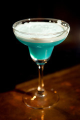 Cocktail of blue color in a glass in the interiors of the bar.