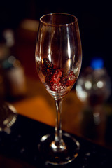 Blackberry in a glass with champagne in the interiors of the bar. Making a cocktail.