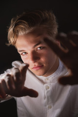 Expressive teenager in a white shirt in bright light, emotional young man with strong hands and beautiful eyes