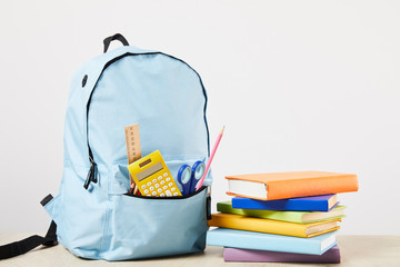 blue backpack with school supplies near books isolated on white - obrazy, fototapety, plakaty