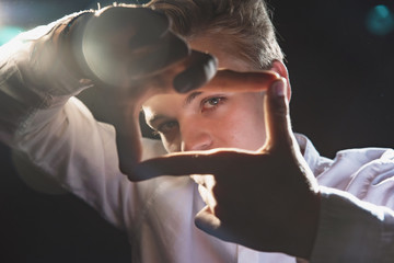 Expressive teenager in a white shirt in bright light, emotional young man with strong hands and beautiful eyes