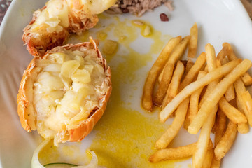 Close up of a lobster tail and some french fries.