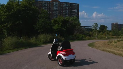 Motorized mobility scooter for elderly and or disabled. Recreational electric ability vehicle for handicapped footage movement from side. Accessibility concept. Camera panning over.