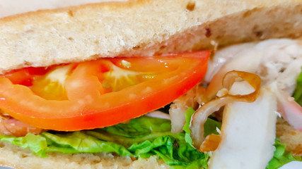 Ciabatta sandwich with lettuce, chicken and cheese on a wooden table