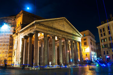 View of the Pantheon against dark blue sky with full moon behind clouds