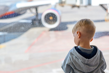 Two year old boy at the airport looking at plane