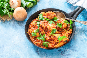 Smoky chicken and mushrooms with tomto sauce in a frying pan
