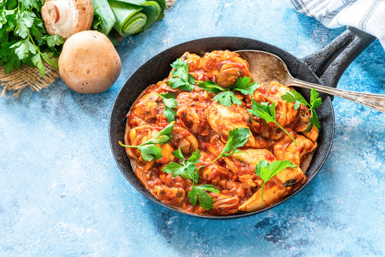 Smoky chicken and mushrooms with tomto sauce in a frying pan