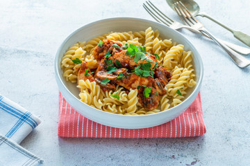 Smoky chicken and mushrooms with tomto sauce and pasta in a bowl