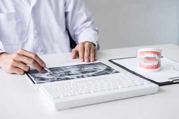 Male doctor or dentist working with patient tooth x-ray film, model and equipment used in the treatment and analysis teeth disease of dental and dentistry at workplace