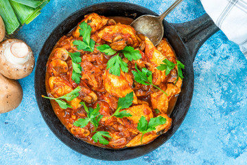 Smoky chicken and mushrooms with tomato sauce in frying pan - overhead view
