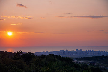 Sunset over the sea and the city on the shore.