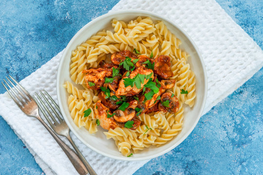 Smoky chicken and mushrooms with tomto sauce and pasta in a bowl - overhead view