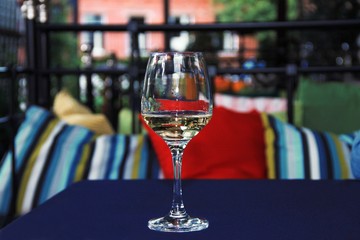 Glass of white wine on a table in a cafe. Copy space, close up.