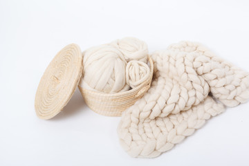 Basket with balls of Merino wool and plaid large knit on a white background.