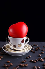 coffee Cup with a toy heart on a stone table with scattered coffee beans, abstraction love for coffee