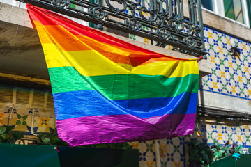 Rainbow flag of the LGBT community blown in the wind on the building. Love, freedom, equality of rights concepts.