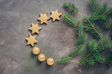 Beautiful round christmas frame from fir branches, golden balls and stars on a dark rustic background. Top view, flat lay, copy space.