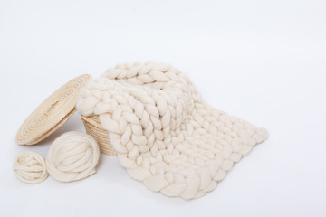 Basket with balls of Merino wool and plaid large knit on a white background.