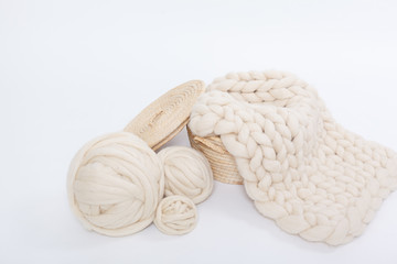 Basket with balls of Merino wool and plaid large knit on a white background.
