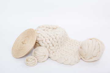 Basket with balls of Merino wool and plaid large knit on a white background.