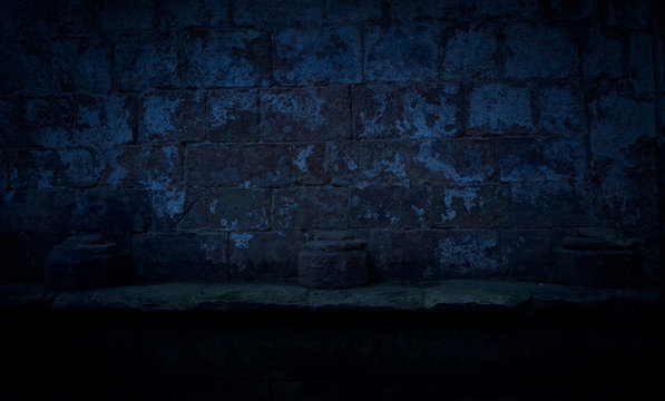 A dark and spooky backgrounf of three plinths on a stone shelf in the ruins of an old monastery at night