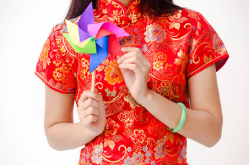 Portrait of American Chinese woman wearing traditional Cheongsam clothes and playing Colorful pinwheel toy,Wind turbine or Wind mill in Chinese New Year festival on white background