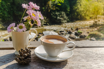 A cup of coffee  on brown desk wood and blur stream view background.