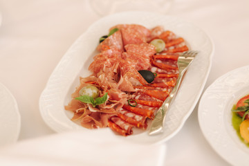 Appetizer in restaurant. Banquet concept. cold meat plate with prosciutto, slices ham, salami, decorated with olive